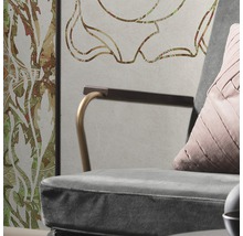 Detailopname van een fauteuil met kussen voor een muur met bloemmotief
