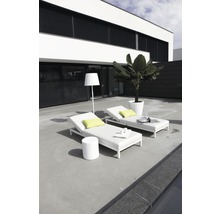 Twee witte tuinligbedden met een tafel en een staande lamp op een terras