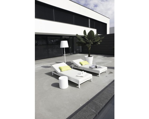 Twee witte tuinligbedden met een tafel en een staande lamp op een terras