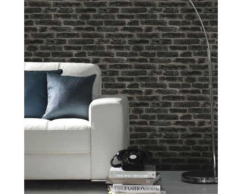 Woonkamer met behang in steenlook, witte bank en staande lamp.