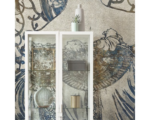 Decoratieve woonkamer met een witte glazen kast tegen een gedessineerd behang.