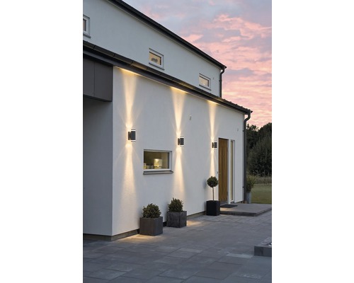 Buitenkant van een huis met buitenwandlampen die de entree verlichten