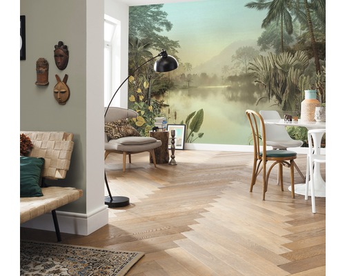 Woonkamer met tropisch fotobehang, houten vloer in visgraatmotief, zitmeubelen en vloerlamp.