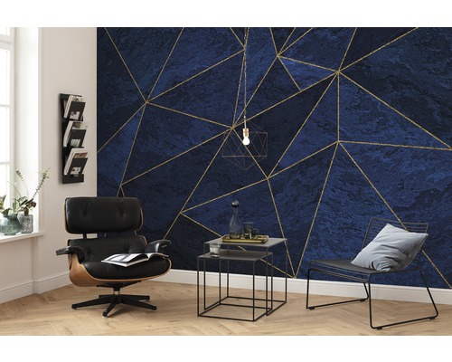 Woonkamer met blauw-goud geometrisch patroonbehang, fauteuil en bijzettafels.