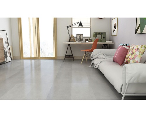 Lichte woonkamer met bank, bureau en vloertegels.