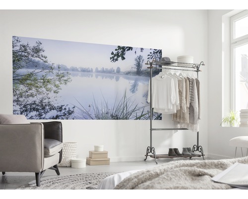 Woonkamer met muurschildering van een meer in de ochtendmist, fauteuil en kledingrek