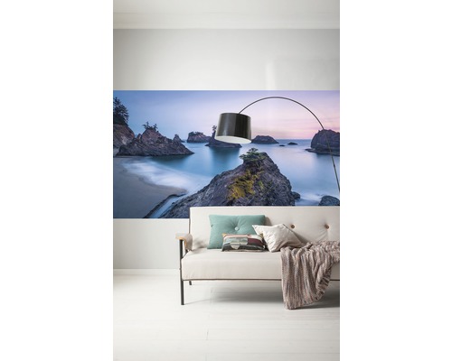 Wanddecoratie met strandlandschap boven een bank met vloerlamp