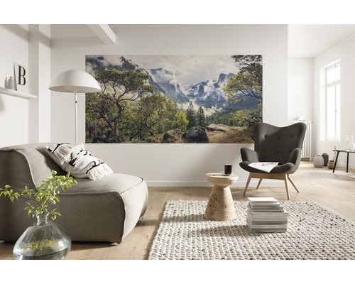 Lichte woonkamer met fauteuil, bank en muurschildering met natuurmotief