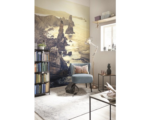 Woonkamer met fotobehang van een kustlandschap, fauteuil, staande lamp en boekenkast