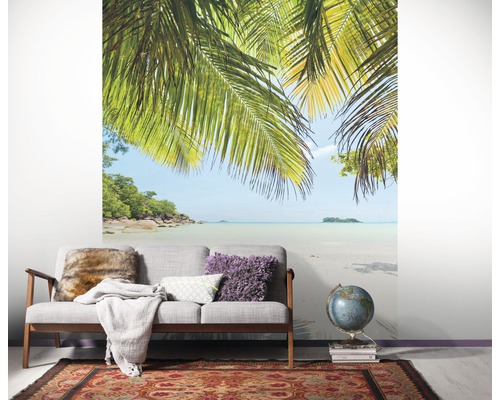Woonkamer met fotobehang van een tropisch strand en palmbomen