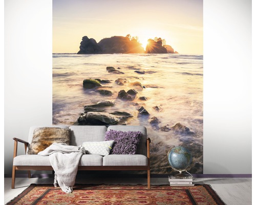 Kamerimpressie met fotobehang van een strand met rotsen in de zee bij zonsopgang