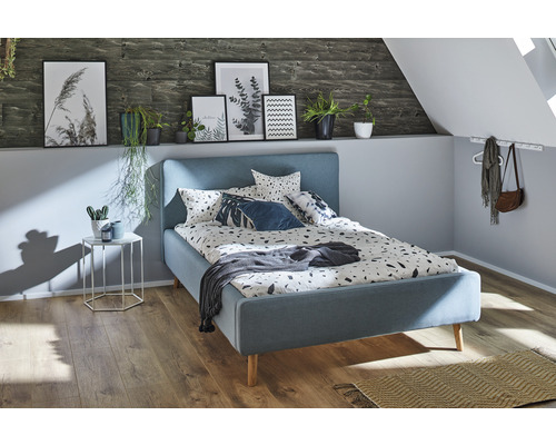 Slaapkamer met blauw bed, nachtkastje en decoraties