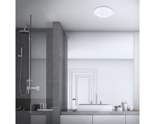 Badkamer met douche, wastafel en ronde plafondlamp