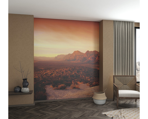 Woonkamer met fotobehang van een berglandschap bij zonsondergang.