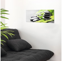 Decoratieve glazen print met zenmotief boven een bank