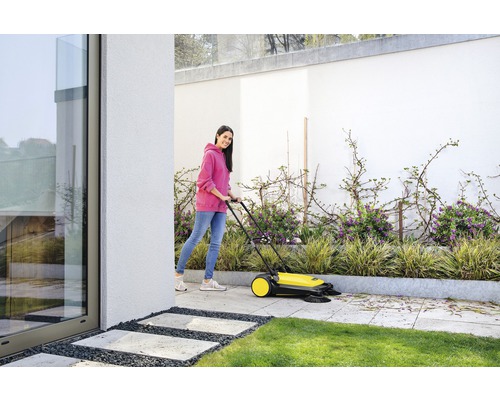 Vrouw gebruikt een veegmachine om een terras schoon te maken
