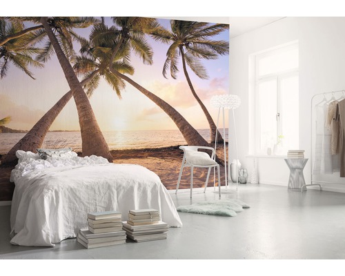 Lichte slaapkamer met fotobehang dat een strand met palmbomen voorstelt.