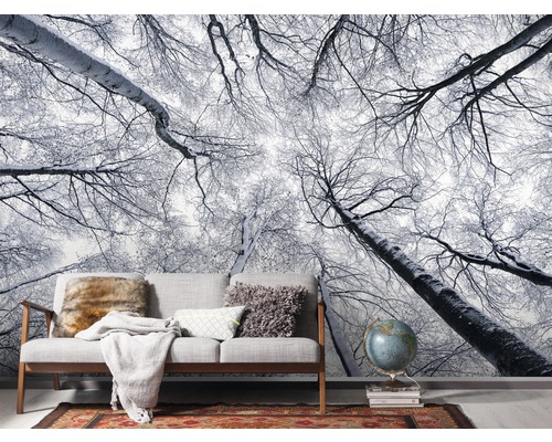 Fotobehang met winterbosmotief in woonkamer met bank en decoraties.