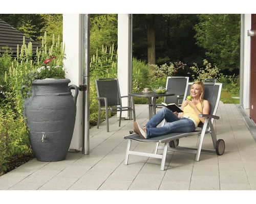 Tuinscène met regenwateropslag, tuinmeubelen en een ontspannende persoon