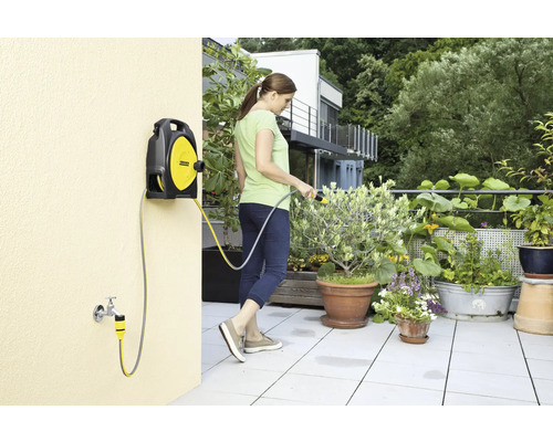 Vrouw geeft planten water met een Kärcher slangbox op een terras