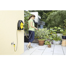 Vrouw bewatert planten met een Kärcher slangbox op een terras