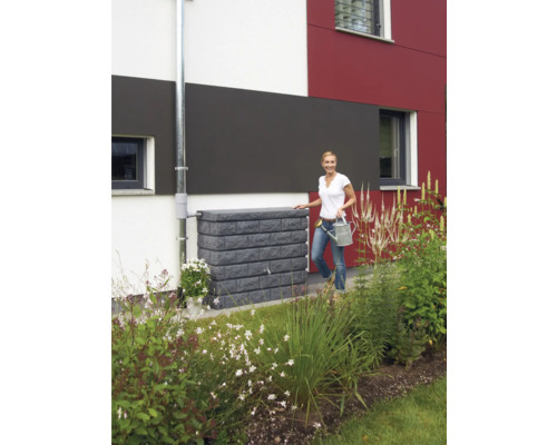 Watertank met baksteenlook naast een huis met een vrouw met een gieter