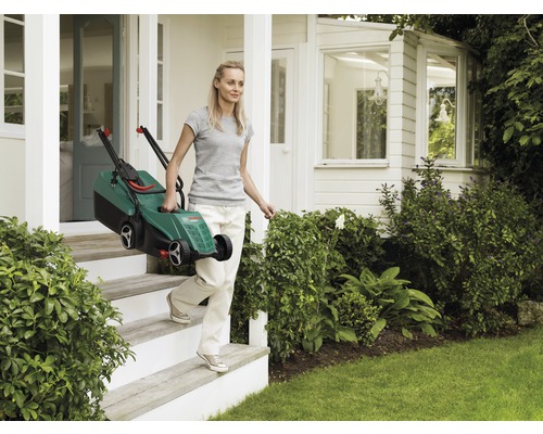 Vrouw draagt een elektrische grasmaaier de trap af