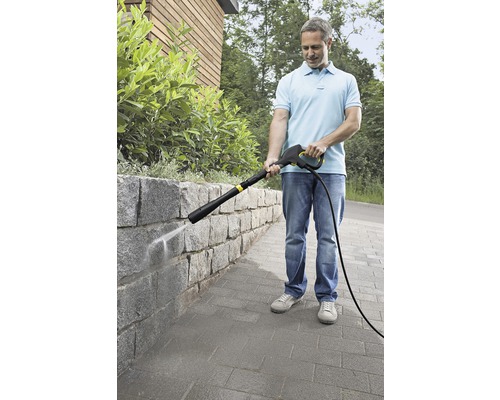 Een man reinigt een stenen muur met een hogedrukreiniger.