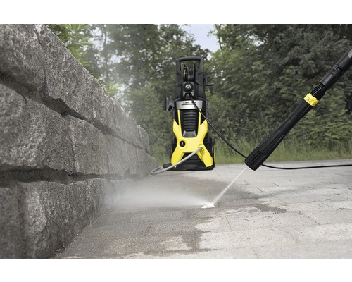 Hogedrukreiniger in gebruik voor het reinigen van een stenen muur en een stenen vloer.