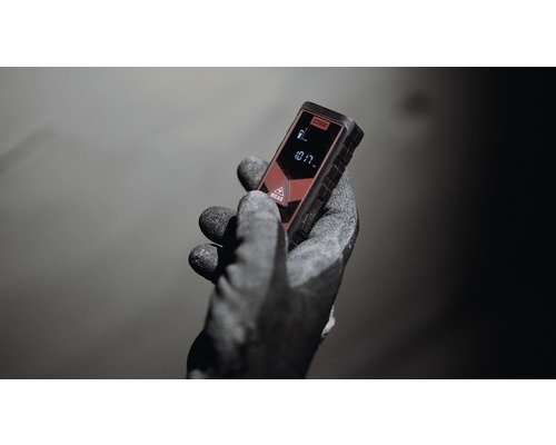 Een hand met werkhandschoen houdt een laser afstandsmeter vast.