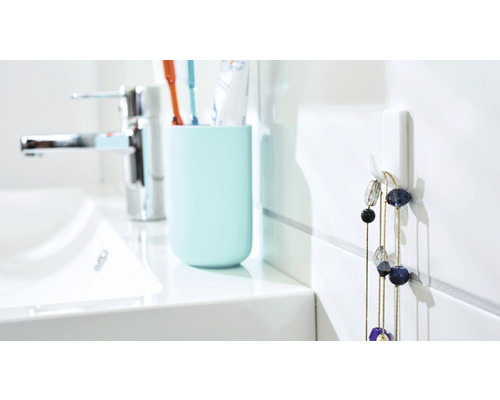 Lichte badkamer met wastafel, tandenborstelbeker en wandhaak met halsketting