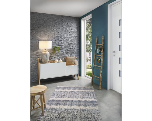 Woonkamer met stenen muur, dressoir, lamp, vloerkleed en houten ladder