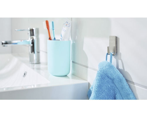 Lichte badkamer met wastafel, tandenborstelbeker, handdoekhaak en blauwe handdoek