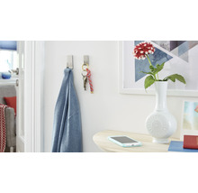 Scene met twee zelfklevende haken waar een shirt en een sleutelbos aan hangen, plus een tafel met een bloemenvaas en smartphone