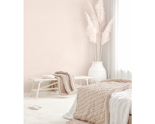 Lichte slaapkamer met bed, bank, dekens, kussens en pampasgras in een vaas