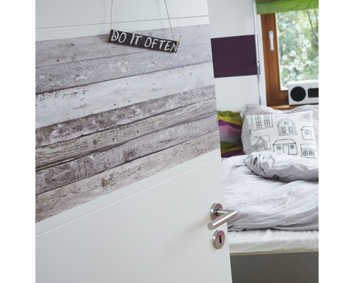 Gedeeltelijk uitzicht op een kamer met een open deur, versierd met houtlookbehang en een bordje met de tekst ''Do it often''