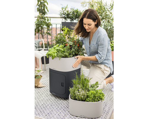 Vrouw met kruidentuin op balkon met plantenbakken en kruiden