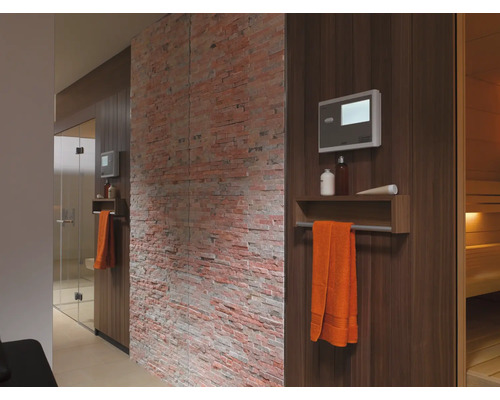 Interieur van een sauna met houten panelen, handdoek, bediening en decoratieve bakstenen muur