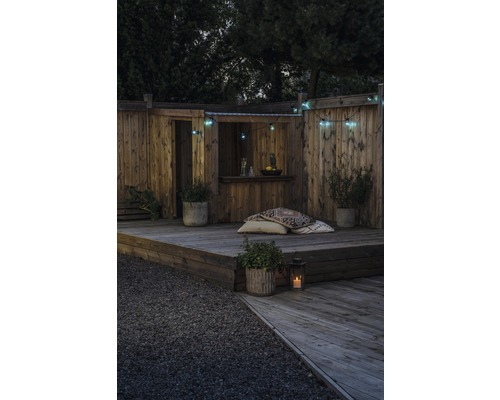 Houten terras met bar, decoratieve verlichting en plantenbakken voor een gezellige tuininrichting.