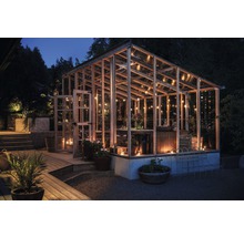 Kas met houten frame, glazen wanden en verlichting in de tuin ''s nachts.