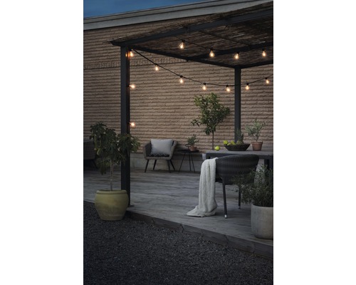 Buitenruimte met pergola, lichtsnoer en tuinmeubelen op een houten terras