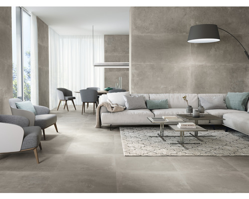 Lichte woonkamer met grijze vloertegels, bank, fauteuils en eettafel