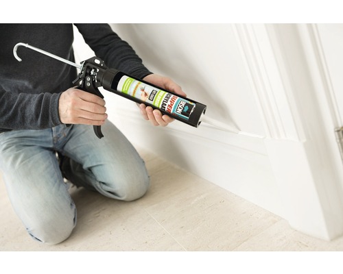 Man dicht plint af met acrylaat uit koker met kitpistool.