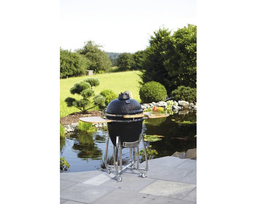 Keramische barbecue op wielen in tuin met vijver