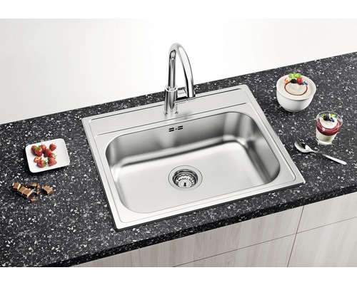 Roestvrijstalen spoelbak met kraan op een aanrecht met etenswaren.