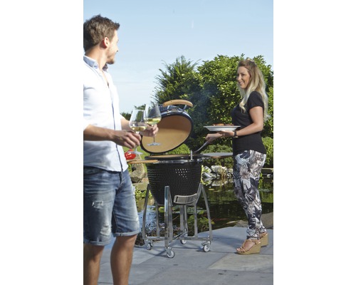 Buitenscène met een keramische barbecue, twee personen en tuindecoratie.