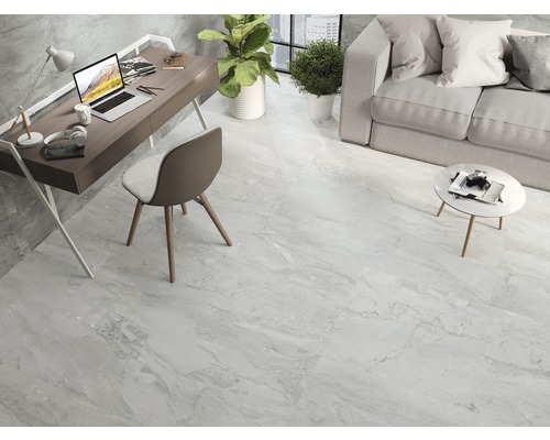 Lichte woonkamer met tegelvloer in marmerlook, bureau, bank en planten.