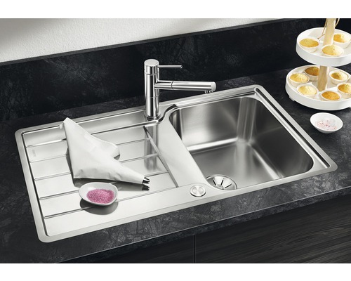 Roestvrijstalen spoelbak met mengkraan, spuitzak en roze suikerstrooisel