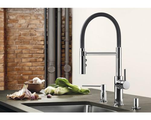 Keukenscène met gootsteenmengkraan, zeepdispenser en groenten op een aanrecht.