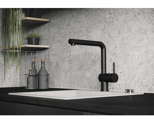 Zwarte keukenkraan op een wasbak met decoratieve items op planken